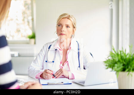 Aufnahme der Ärztin im Gespräch mit Frau und der Diskussion über die medizinischen Bericht im Zimmer des Arztes. Stockfoto