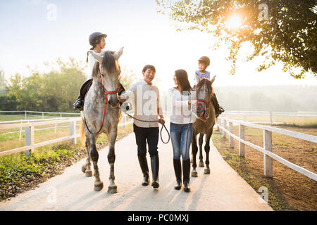 Fröhlicher junger chinesischen Familie reiten pferde Stockfoto