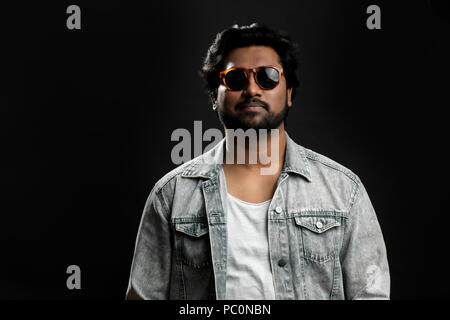 Indische Mafia. Tolle Schauspieler Sonnenbrille tragen. starker Mann in Jacke und T-Shirt auf dem schwarzen Hintergrund isoliert. Übermütige Stockfoto