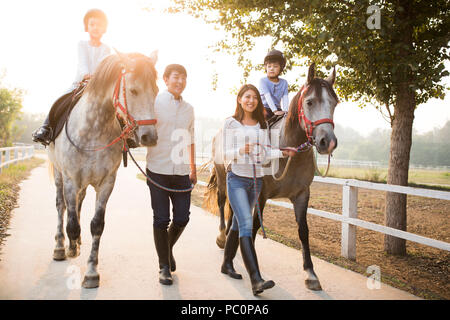 Fröhlicher junger chinesischen Familie reiten pferde Stockfoto