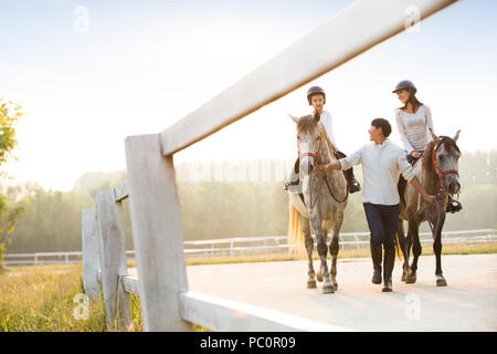 Fröhlicher junger chinesischen Familie reiten pferde Stockfoto