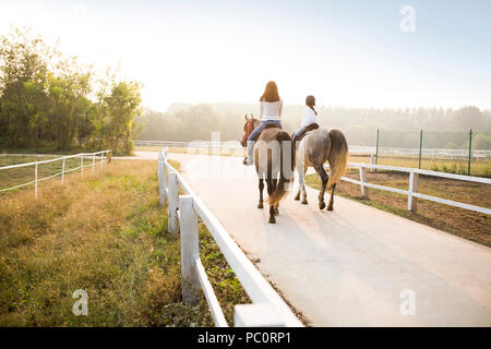 Junge chinesische Mutter lehre Tochter Reiten Stockfoto