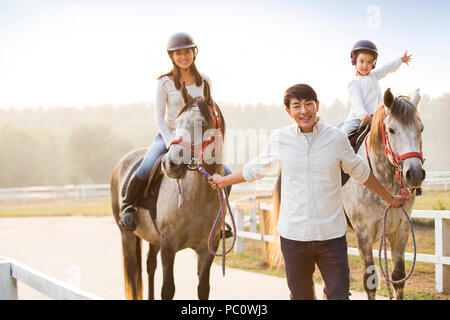 Fröhlicher junger chinesischen Familie reiten pferde Stockfoto