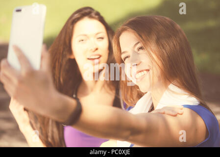 Millennials lifestyle Konzept - zwei Sport Mädchen nehmen eine selfie und Lächeln beim Training im Freien an einem sonnigen Tag (Vintage Effekt) Stockfoto