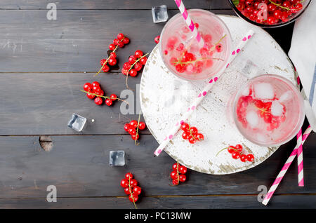 two glasses with a cocktail of red currant and ice and berries in bowl on a dark background, copy space Stockfoto