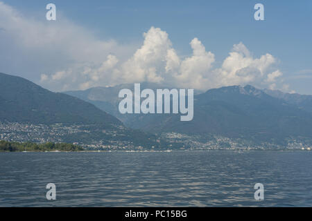 Lago Maggiore See Landschaft mit Berg Wasser und bewölkter Himmel im Sommer vom Boot aus Stockfoto