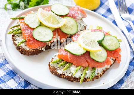 Toast mit Lachs, Spargel, Gurken und Frischkäse. Leckere Sandwiches zum Frühstück oder Mittagessen Stockfoto