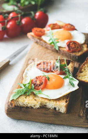 Breakfast Sandwich mit Ei, Käse und Tomaten auf rustikalem Holz Schneidebrett. Detailansicht, selektive konzentrieren. Getonten Bild Stockfoto