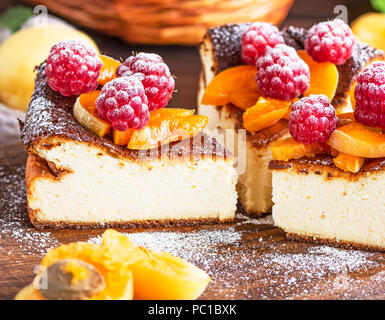 Quark Torte mit Himbeeren und Aprikosen auf einem braunen Holz- Board, in der Nähe Stockfoto