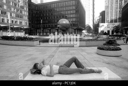 Manhattan, 1982. Mann ruht in World Trade Center Plaza. Die Sphäre der Skulptur und der Brunnen im WTC Plaza. Stockfoto