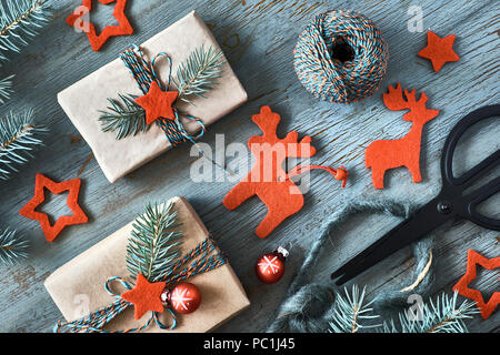 Rustikal Hintergrund in Grün und Rot mit Tannenzweigen und Weihnachtsgeschenke in einfachen braunes Packpapier. Saisonale Hintergrund Schuß von oben. F Stockfoto