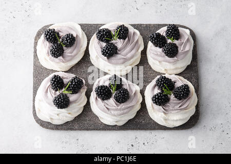 Pavlova Dessert Kuchen mit weichen Lavendel Creme und frische Brombeeren am grauen Stein Schneidbrett, weiß strukturierten Hintergrund Stockfoto