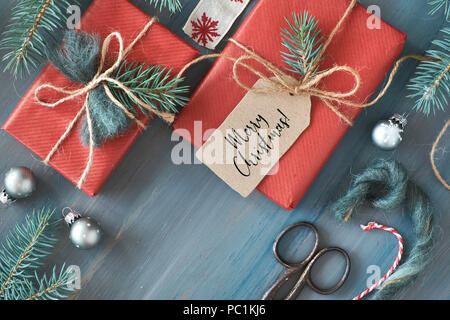 Rustikal Hintergrund mit Tannenzweigen und Weihnachtsgeschenke Geschenk auf rotem Papier eingewickelt. Saisonale Hintergrund Schuß von oben. Flach, Ansicht von oben, Stockfoto