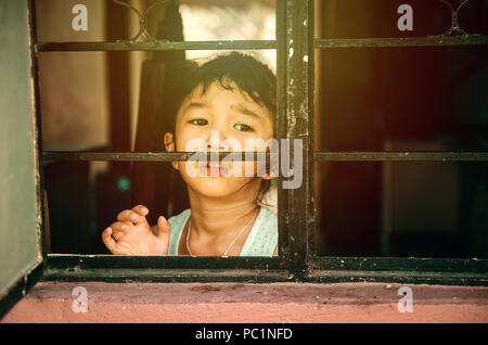 Ein trauriges mädchen aus dem Fenster warten auf jemanden oder um Hilfe zu bitten. Stockfoto