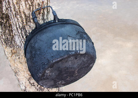 Alten schwarzen Topf an durch den Einsatz von Kochen für eine lange Zeit am Baum hängen. Stockfoto