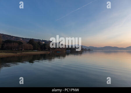 Ein Shooting für einen Sonnenuntergang über einem See, mit schönen, warmen Farben und viele diagonalen Linien durch Wolken und Wasser Wellen erstellt Stockfoto