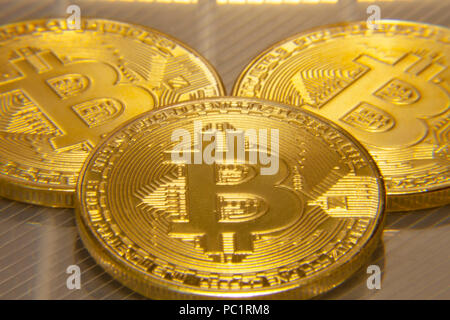 Makro Nahaufnahme: drei physischen golden Bitcoins (digitale virtuelle crypto-Währung) auf einer semi-transparente Oberfläche. Stockfoto