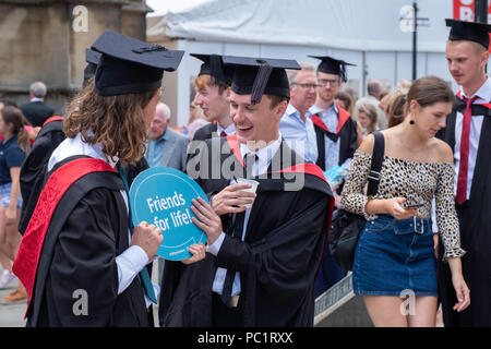 Menge junger Männer feiern Staffelung Holding unterzeichnen, 'Freunde fürs Leben' nach der Abschlussfeier in Bristol, England YK. Stockfoto