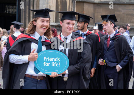 Menge junger Männer feiern Staffelung Holding unterzeichnen, 'Freunde fürs Leben' nach der Abschlussfeier in Bristol, England YK. Stockfoto