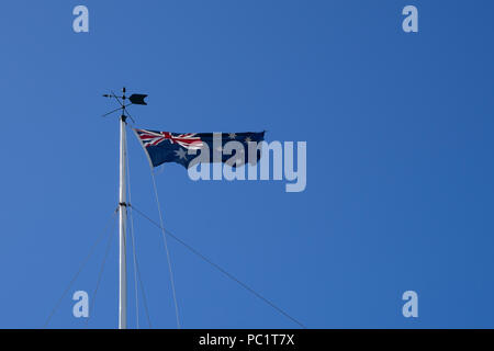 Nationale Australien Flagge auf der Pole, weht im Wind auf und blauer Himmel an einem sonnigen Tag. Stockfoto