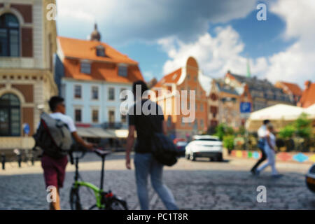 Touristen zu Fuß mit dem Fahrrad mit einer bunten und lebhaften Viertel im Zentrum der Altstadt von Riga an einem sonnigen Tag. Verschwommen Stockfoto