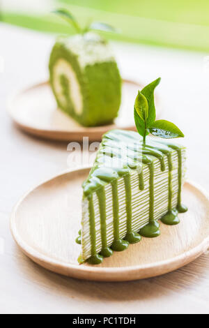 Close up Green tea roll Kuchen auf Holz- Teller, flache Tiefenschärfe, Schwerpunkt auf der Teeblätter. Stockfoto