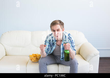 Mann mit Bier und Chips vor dem Fernseher zu Hause Stockfoto