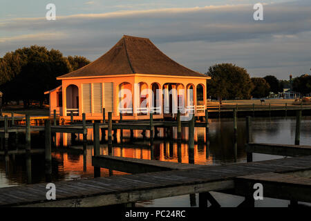 Ein goldenes 'Magic Hour' Sonnenuntergang taucht ein einsamer Bootshaus, und seine Reflexion, in einem dunkleren Marina, Whalehead Club, Corolla, Outer Banks, NC Stockfoto