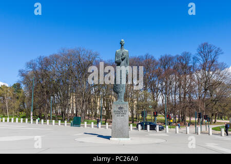 OSLO, Norwegen, 26. April 2018: Die Statue von König Haakon VII. von Norwegen, hinter den Bäumen sehen Sie die Königliche Residenz Stockfoto