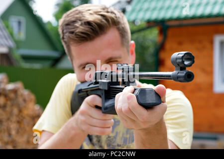 Junger Mann schiessen mit Luftgewehr. Stockfoto