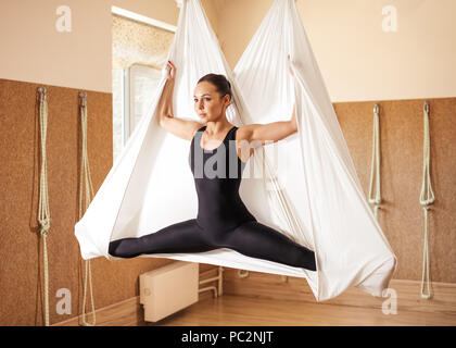 Wunderschön inspirierten Mädchen tun Antenne Yoga auf weiß Hängematte im Licht Studio. Seitenansicht Foto in voller Länge Stockfoto