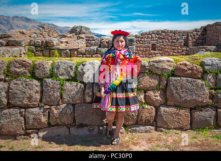 Jungen indigenen Quechua Dame in traditioneller Kleidung und Frisur in der Inka Ruine von tipon in der Nähe der Stadt Cusco. Stockfoto