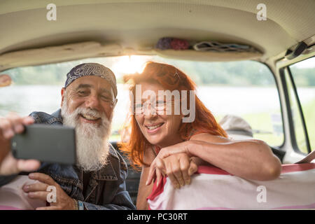 Alte hipster Paar sitzen in einem Auto eine selfie mit einem Telefon Stockfoto