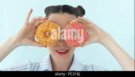 Die Frau ist die Donuts und macht Sonnenbrille von es Stockfoto