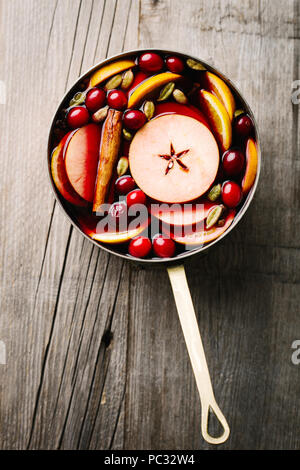 Wein in der Küche Topf mit Obst auf alten Vintage Tabelle Glühwein. Nahaufnahme Stockfoto