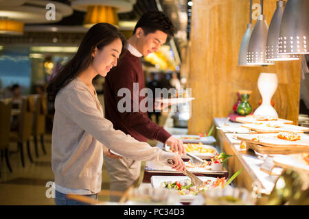 Fröhliche junge chinesische Paar Essen vom Buffet Stockfoto