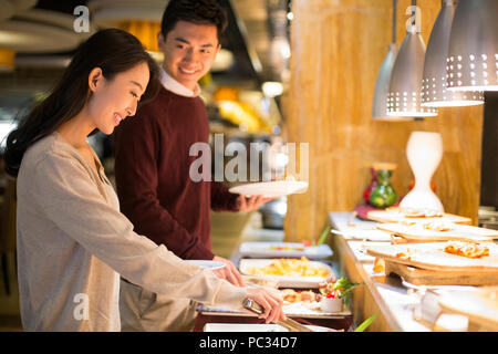 Fröhliche junge chinesische Paar Essen vom Buffet Stockfoto