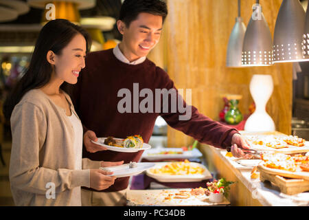 Fröhliche junge chinesische Paar Essen vom Buffet Stockfoto