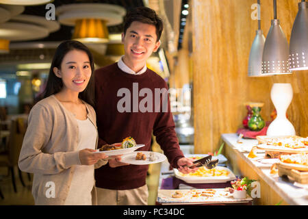 Fröhliche junge chinesische Paar Essen vom Buffet Stockfoto