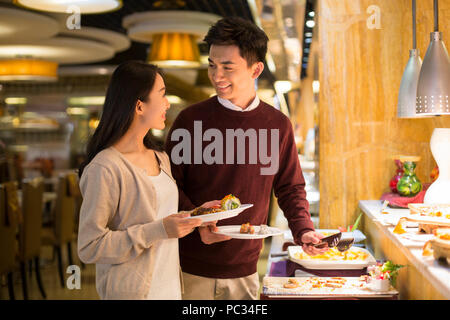 Fröhliche junge chinesische Paar Essen vom Buffet Stockfoto