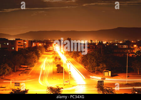 Leichte Wanderwege Fotografie in der Stadt. Lichter der Autos mit bewölktem Himmel und die Berge im Hintergrund. Lange Belichtung & Verschlusszeit erfasst Stockfoto