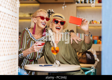 Besten Momente. Schöne Frauen die Bilder gemeinsam begeistert beim Treffen im Cafe Stockfoto