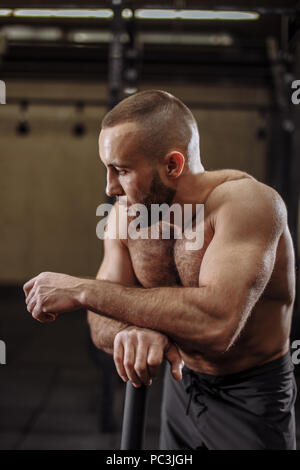 Nachdenklich, verschwitzten Mann lehnt sich auf den Hammer, während an der Turnhalle ausruhen. Nahaufnahme Seite Foto anzeigen Stockfoto
