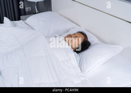 Alte Frau schlafen auf einem Bett im Schlafzimmer Stockfoto