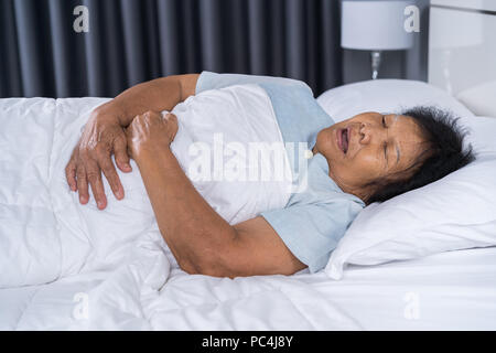 Ältere Frau mit Magenschmerzen im Bett zu Hause Stockfoto