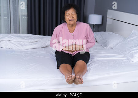 Ältere Frau mit Magenschmerzen im Bett zu Hause Stockfoto