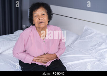 Ältere Frau mit Magenschmerzen im Bett zu Hause Stockfoto