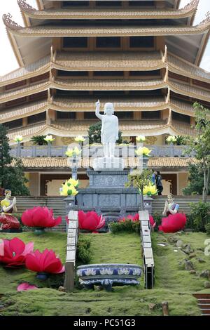 Minh Dang Quang buddhistischer Tempel. Junge Buddha Statue am oberen Ende der Treppe mit langen Ohren, Glatze und einen Finger, der in den Himmel. Ho Chi Minh City. Vietnam. | Verwendung weltweit Stockfoto