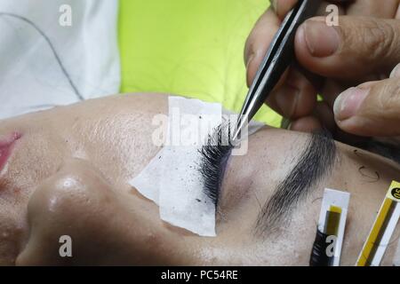 Vietnamesische Beauty Salon. Kosmetikerin Anwendung verlängert die Wimpern zu Frau. Ho Chi Minh City. Vietnam. | Verwendung weltweit Stockfoto