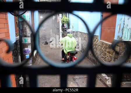 Mann, sccoter in einer kleinen Straße. Ho Chi Minh City. Vietnam. | Verwendung weltweit Stockfoto